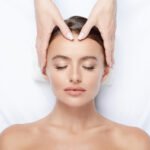 Gorgeous young girl with thick eyebrows and perfect skin doing facial massage, beauty photo concept, hands on face, skin care, relaxing.